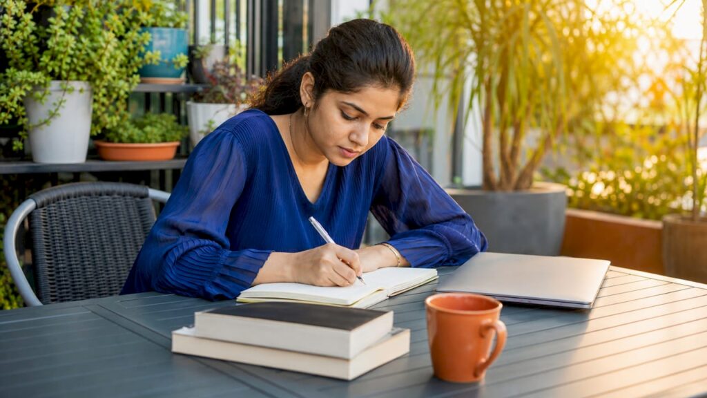 Woman writing career development notes at home office