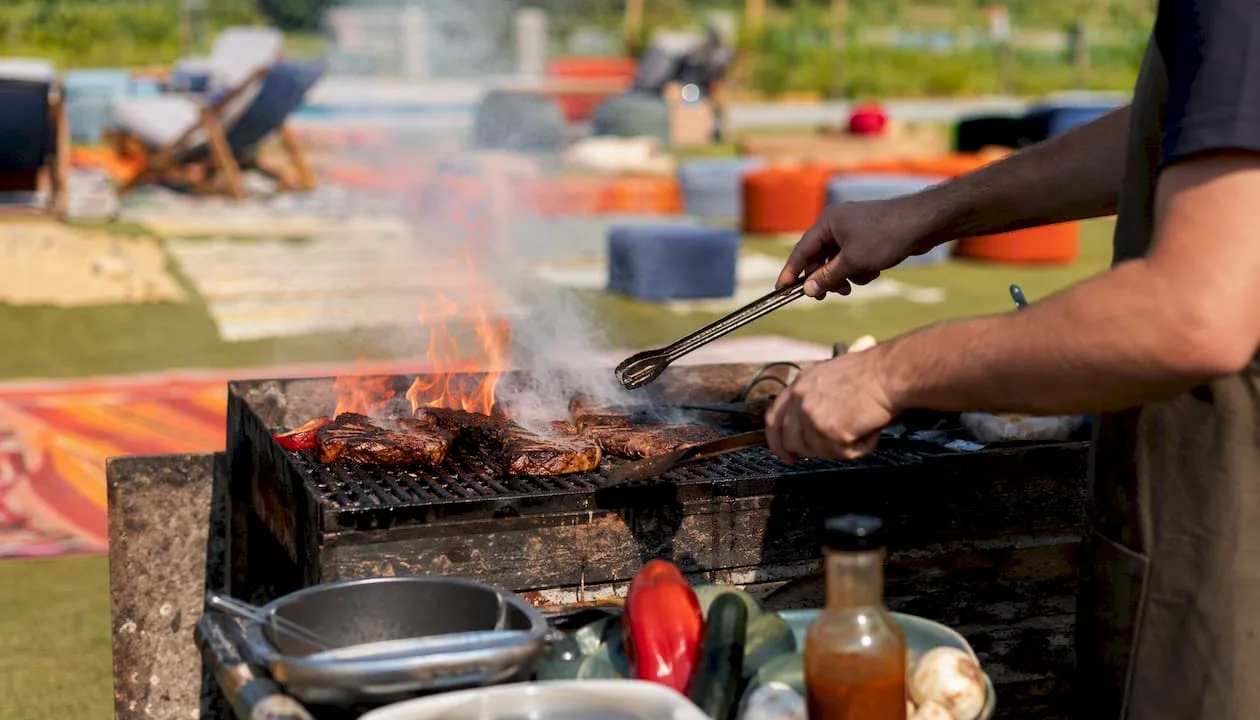 Hands grilling burgers at outdoor barbecue