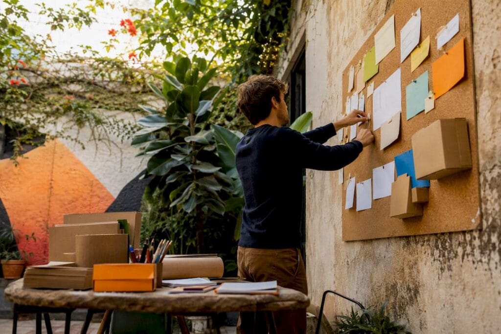 Hands pinning idea cards in startup workspace