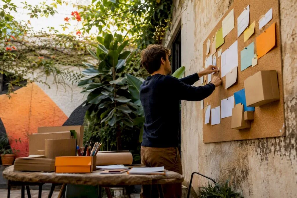 Hands pinning idea cards in startup workspace