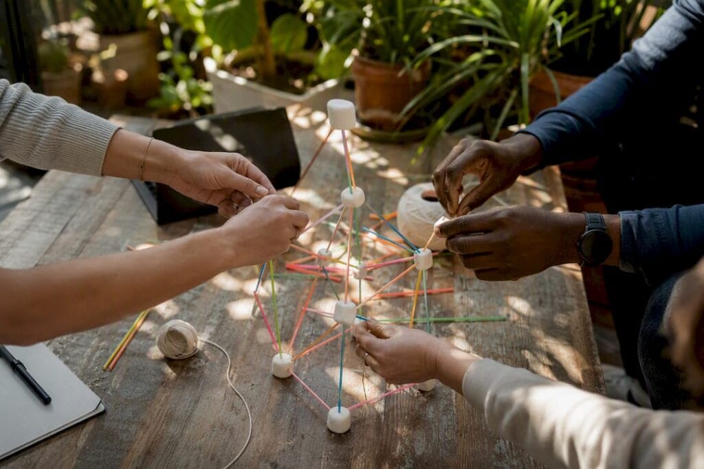 Hands building marshmallow tower on table